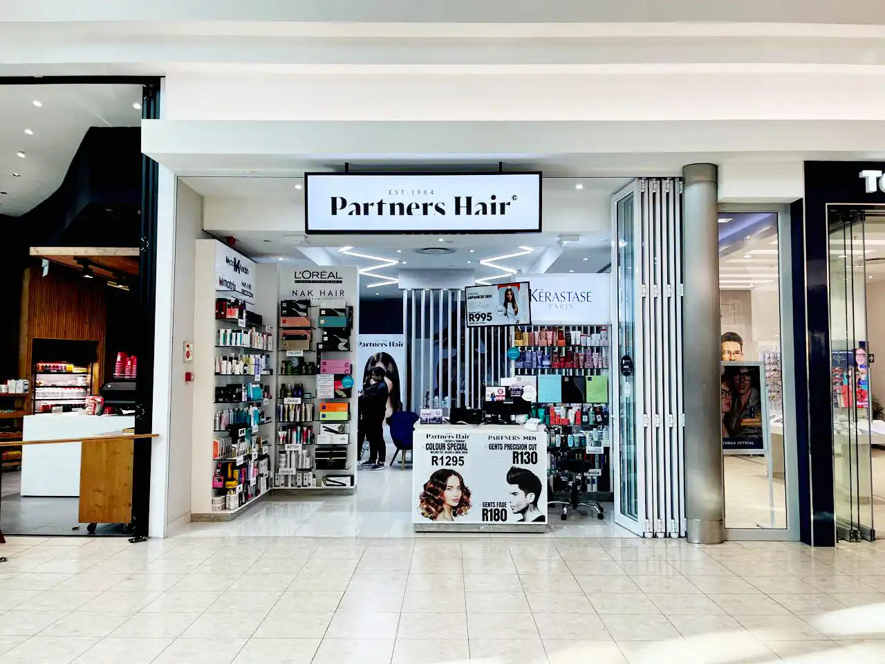 Hair salon storefront named ’Partners Hair’ with product displays visible.