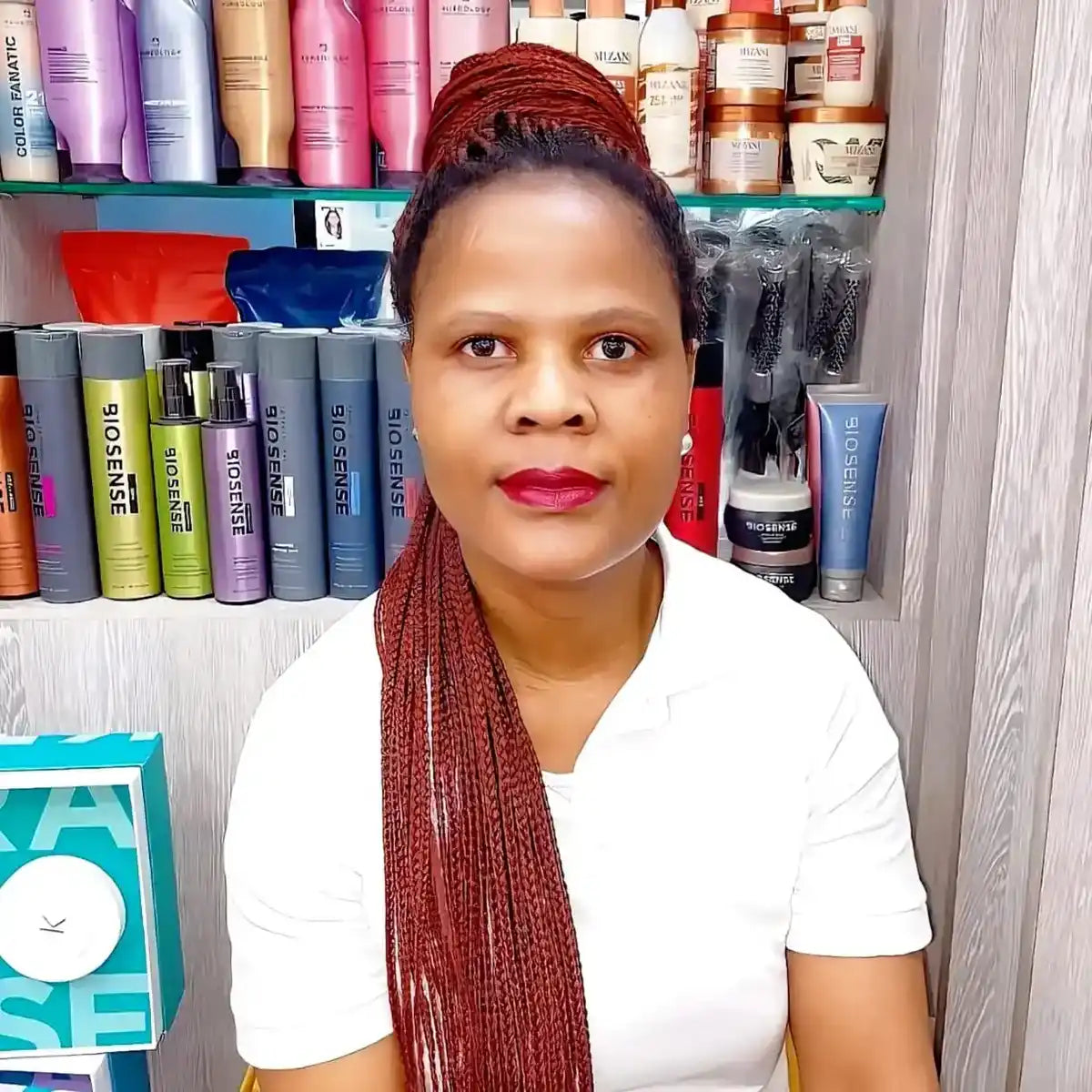 A hairstylist wearing a white t-shirt and long burgundy braids.