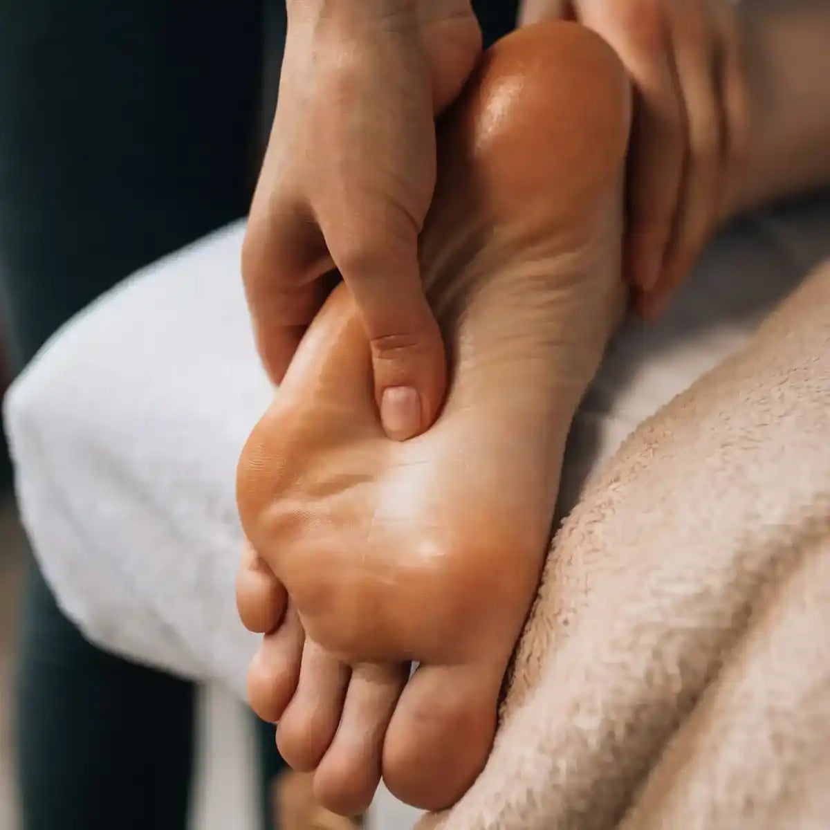 Hands massaging the sole of a bare foot.