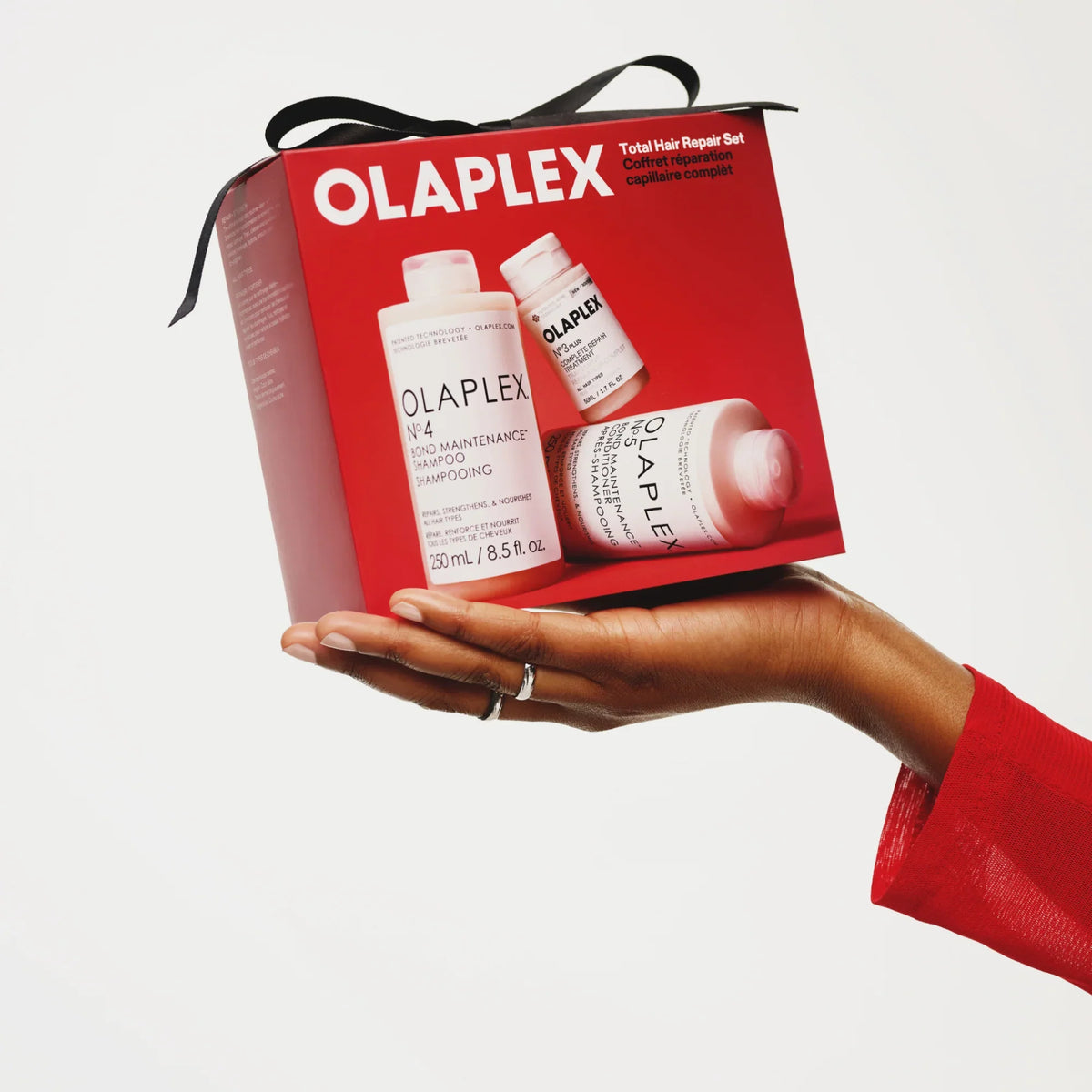 Hand holding the red Olaplex Total Hair Repair Set holiday gift box