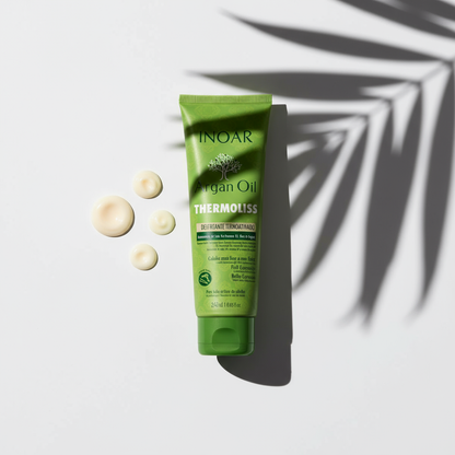 Inoar Argan Oil Thermoliss Anti-Frizz Balm green tube with cream drops and palm leaf shadow