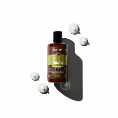 Inoar botanic conditioner with castor oil brown bottle with green label and cream dollops on white background