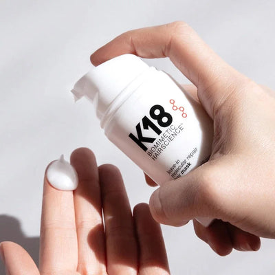 K18 Hair Mask: Hand applying leave-in treatment for damaged hair repair. K18 molecular repair for soft, healthy hair.