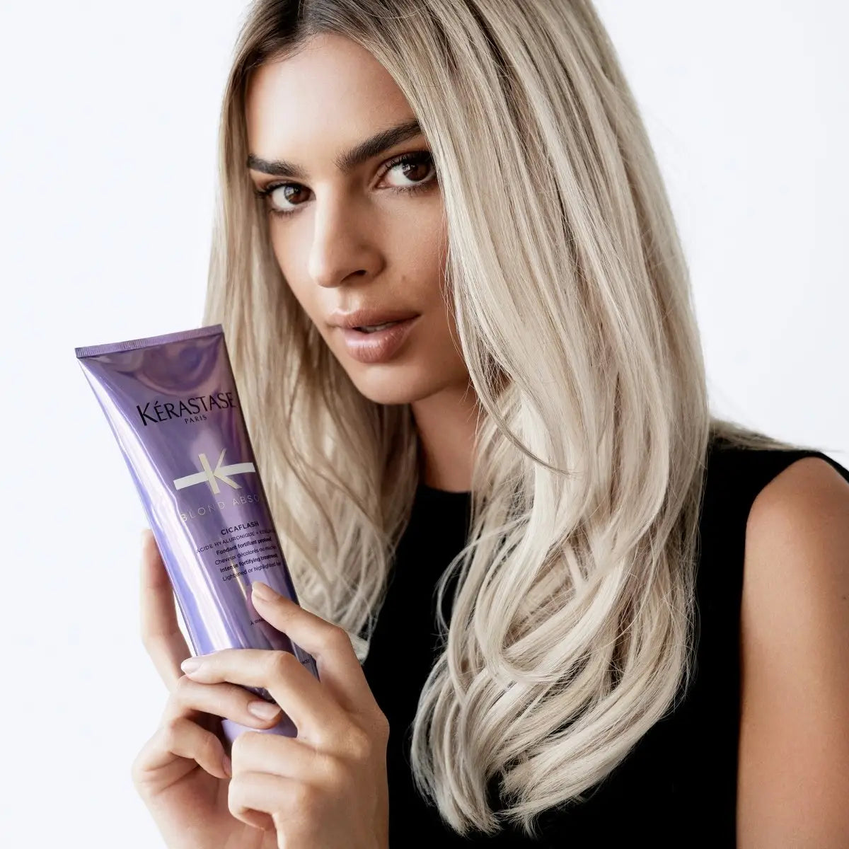 Woman with long blonde hair holding Kerastase Blond Absolu Cicaflash Fondant 250ml tube