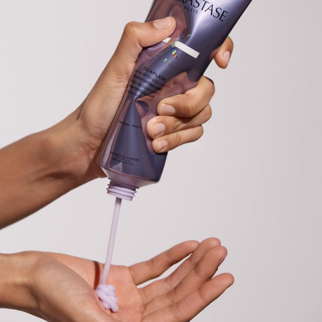 Kerastase Blond Absolu Cicaflash cream being dispensed from a bottle onto a hand