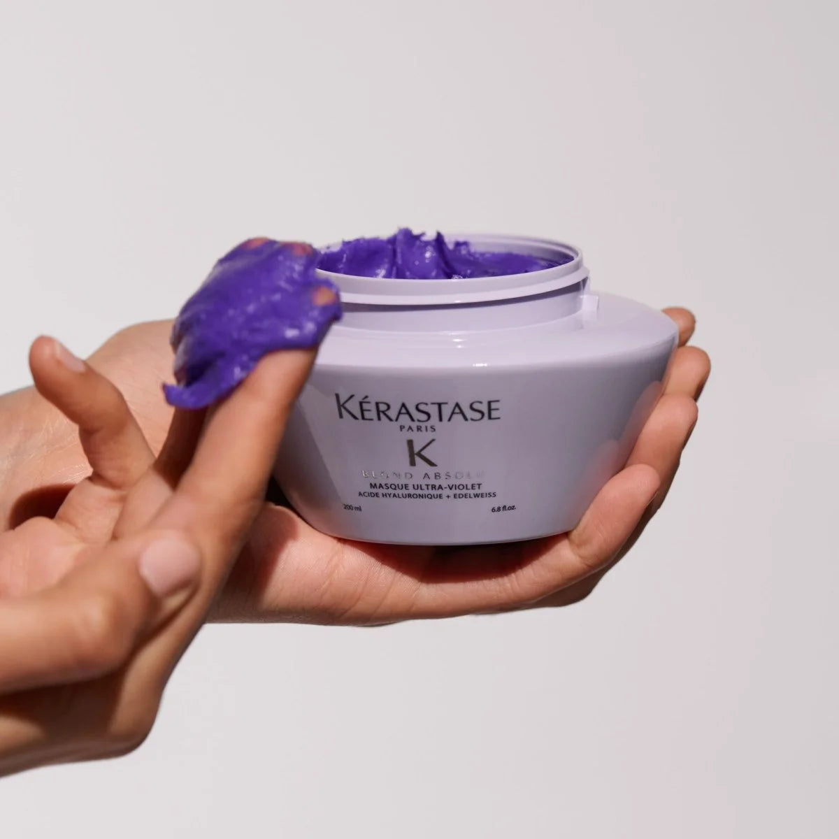 Kérastase Blond Absolu Masque Ultra-Violet Hair Mask 200ml in hand, showcasing its vibrant purple formula for blonde hair care.