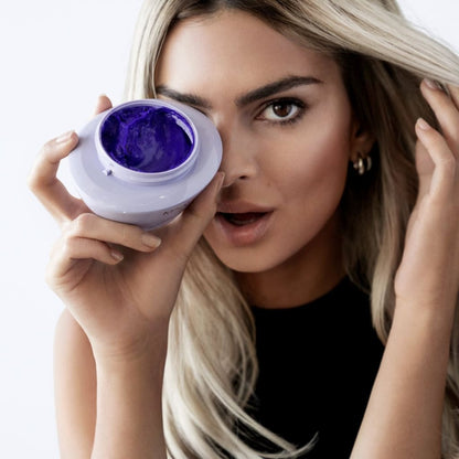 Woman holding Kerastase Blond Absolu Masque with purple hair dye in white container