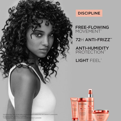 A woman with curly hair and a white tank top using Kerastase Discipline Bain Fluidealiste