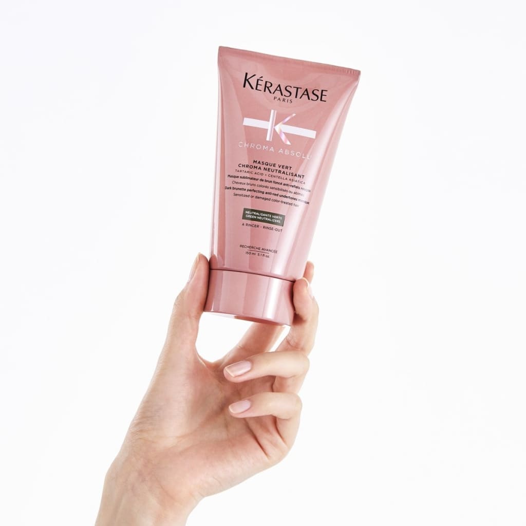 Pink tube of Kérastase Chroma Absolu Masque Vert, held by hand, for dark brunette hair