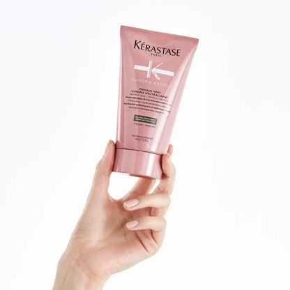 Pink tube of Kérastase Chroma Absolu Masque Vert, held by hand, for dark brunette hair