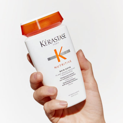 Hand holding a bottle of Kérastase Nutritive Bain Satin shampoo for slightly dry hair