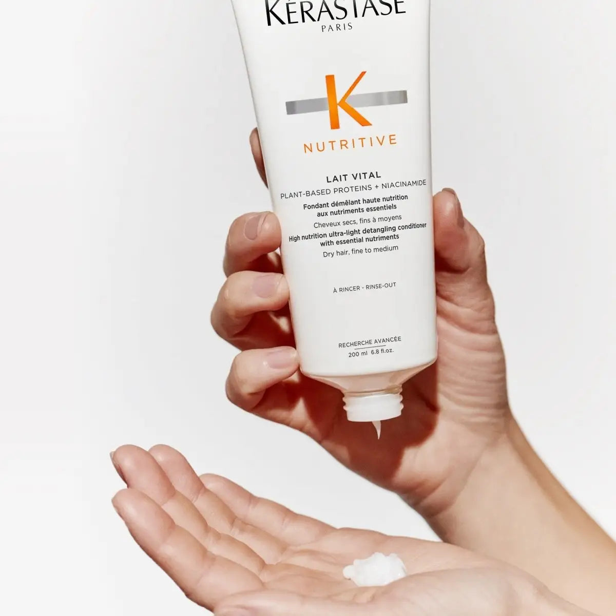 Hand holding Kerastase Nutritive Lait Vital Conditioner with product on palm