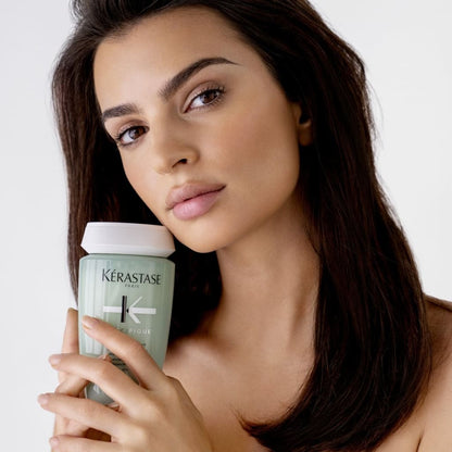 Woman holding a Kérastase Specifique Bain Divalent shampoo 250ml product container