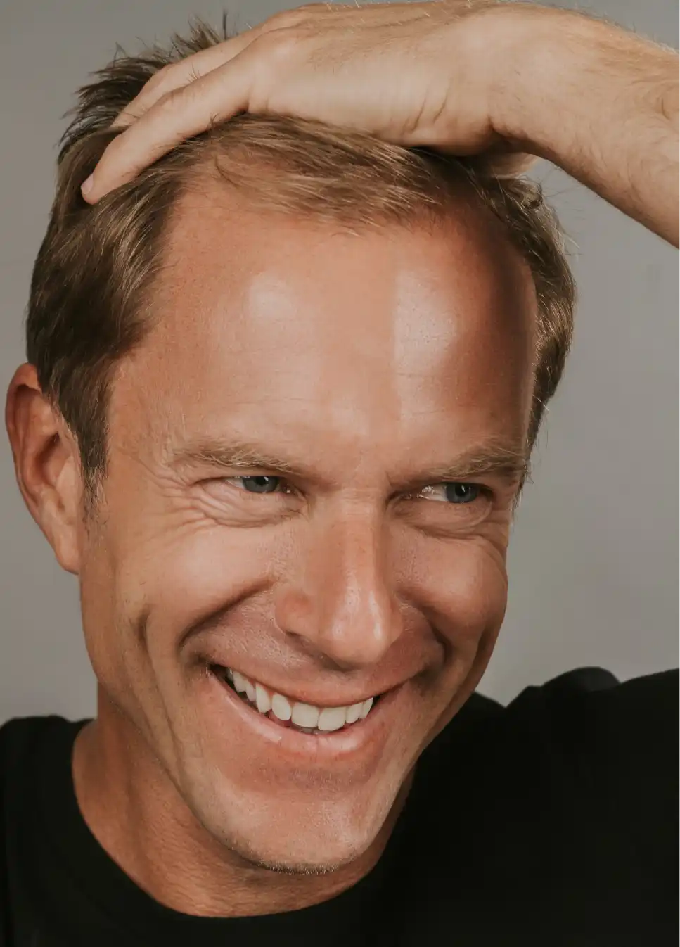 Smiling man with hand on head.