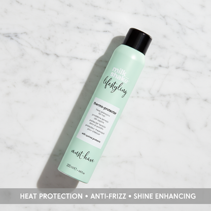Milkshake heat protection spray for hair in a mint green bottle with black cap on marble surface