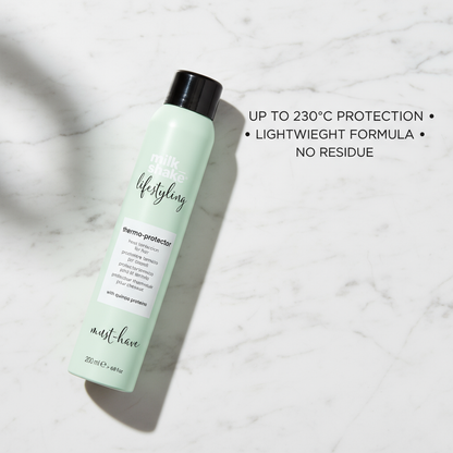 Milkshake heat protection spray for hair in a mint green bottle with black cap on marble surface