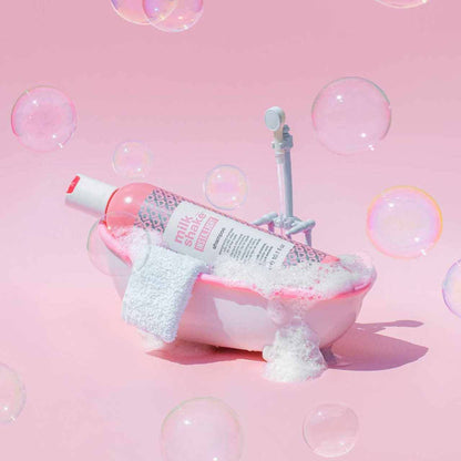 Milkshake Insta.Light Shampoo bottle in a small pink bubble-filled bathtub with white towel on pink background