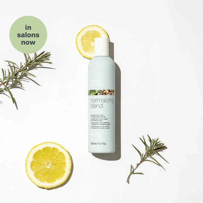 Milkshake Normalizing Blend Shampoo bottle with lemon slices and rosemary branches on white background
