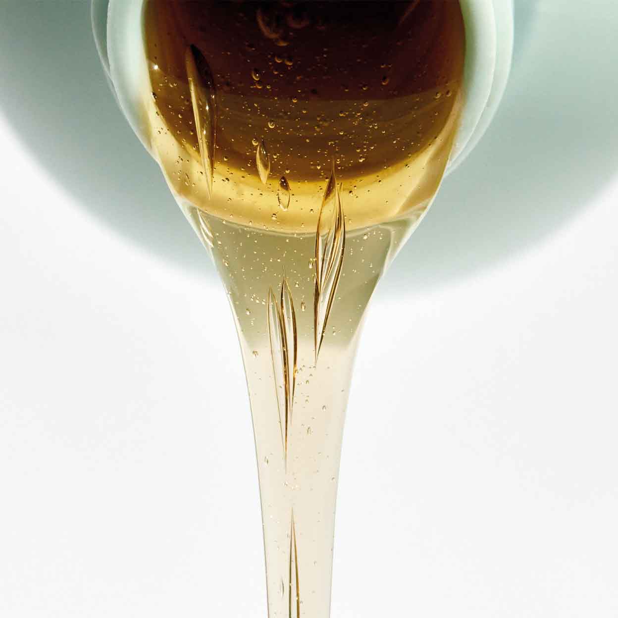 Close-up of Milkshake Normalizing Blend Shampoo golden gel texture pouring from bottle