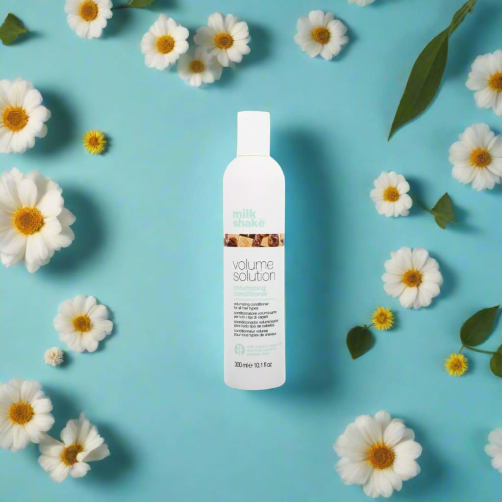 White bottle of Milkshake Volume Solution Conditioner 300ml surrounded by daisies