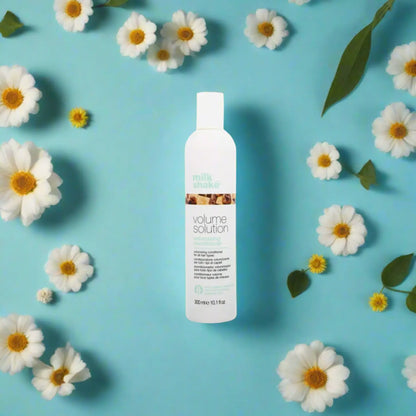 White bottle of Milkshake Volume Solution Conditioner 300ml surrounded by daisies