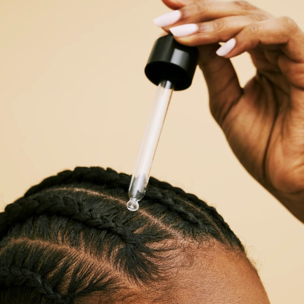 Dropper applying Mizani Miracle Length serum to braided hair for thicker, fuller hair