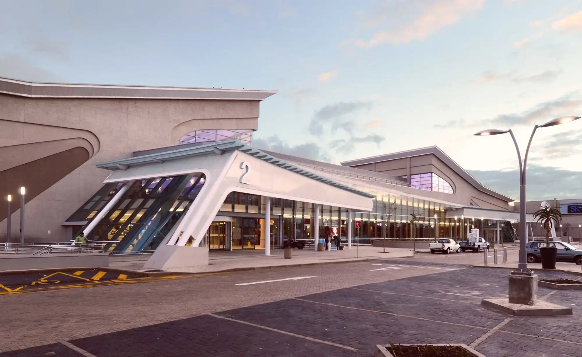 Modern airport terminal building with angular roof design and glass walls.