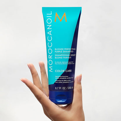 Hand holding Moroccanoil Blonde Perfecting Purple Shampoo for vibrant blonde hair