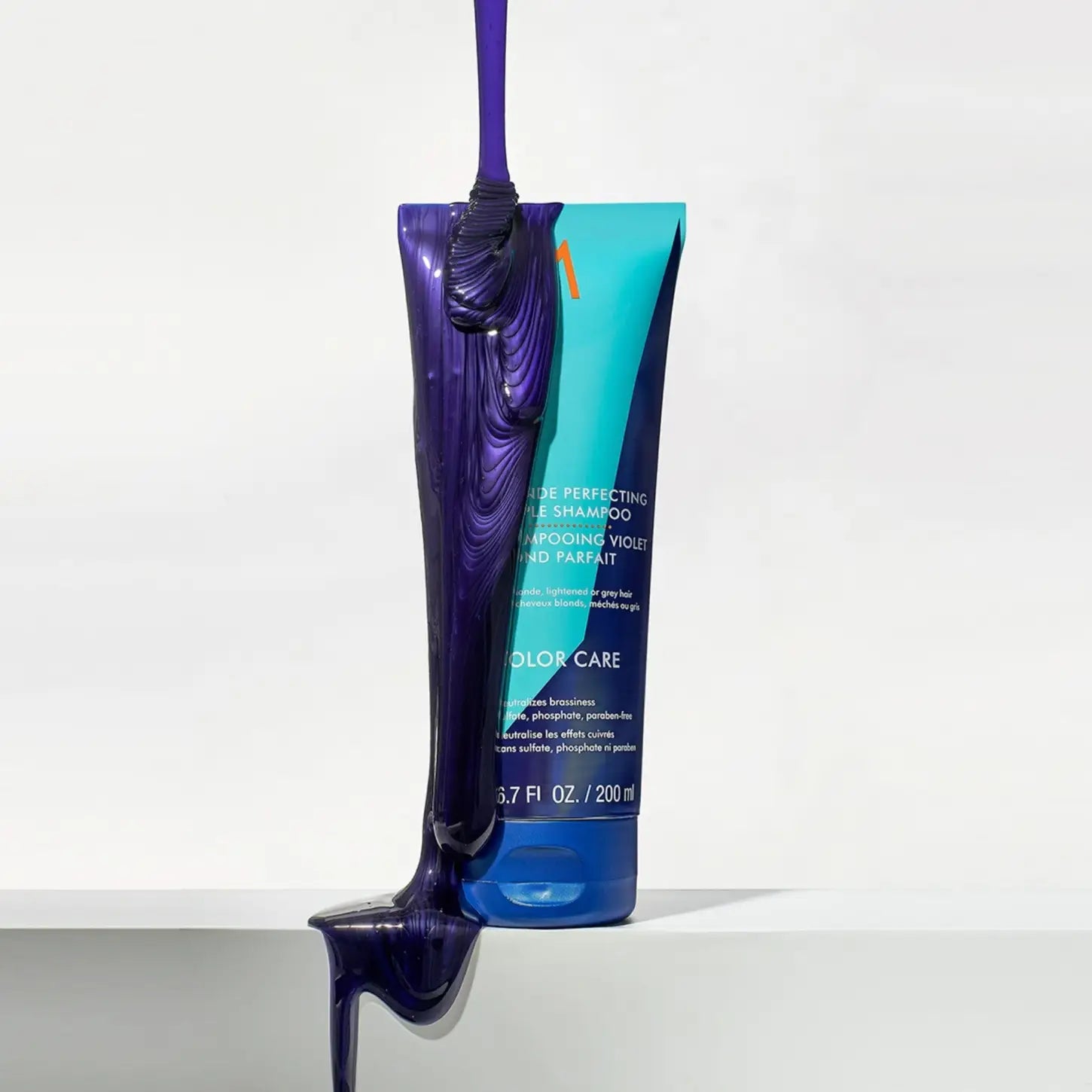 Moroccanoil Blonde Perfecting Purple Shampoo tube with purple liquid pouring out