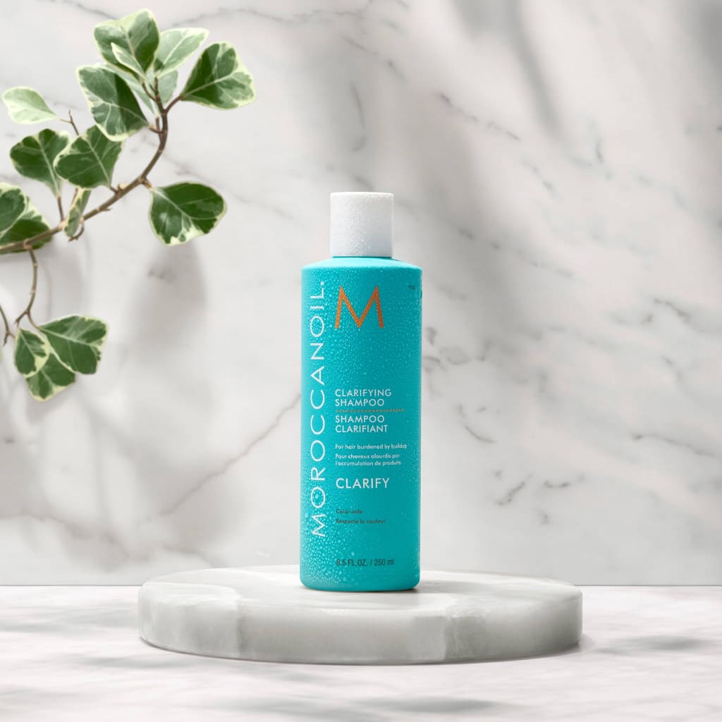 Moroccanoil Clarifying Shampoo: Deep Cleanse, Sulfate-Free. Remove Buildup & Restore Shine. Turquoise bottle on white pedestal.
