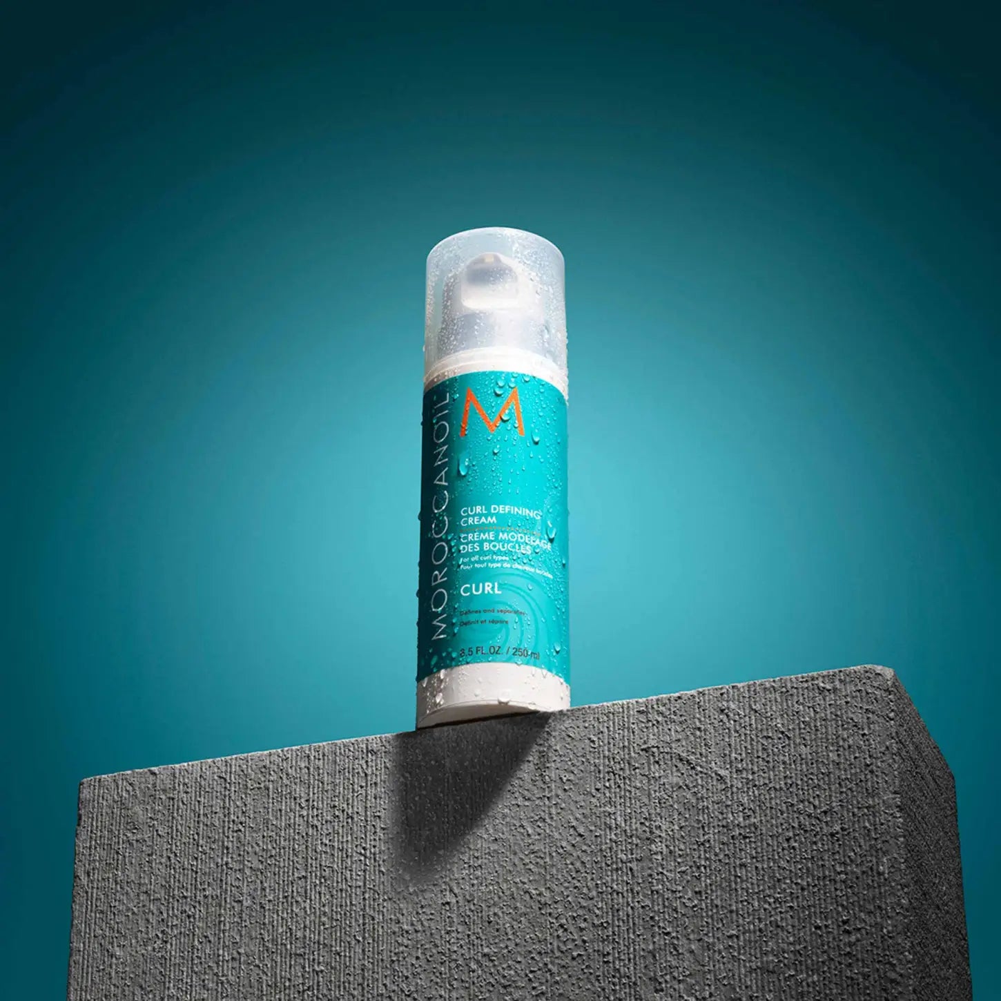 Teal aerosol spray can for Moroccanoil Curl Defining Cream 250ml on gray surface