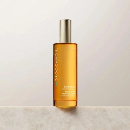 Moroccanoil dry body oil bottle with golden oil and silver cap on marble surface