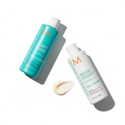 Moroccanoil frizz control bundle with shampoo and conditioner bottles and cream smear on white background