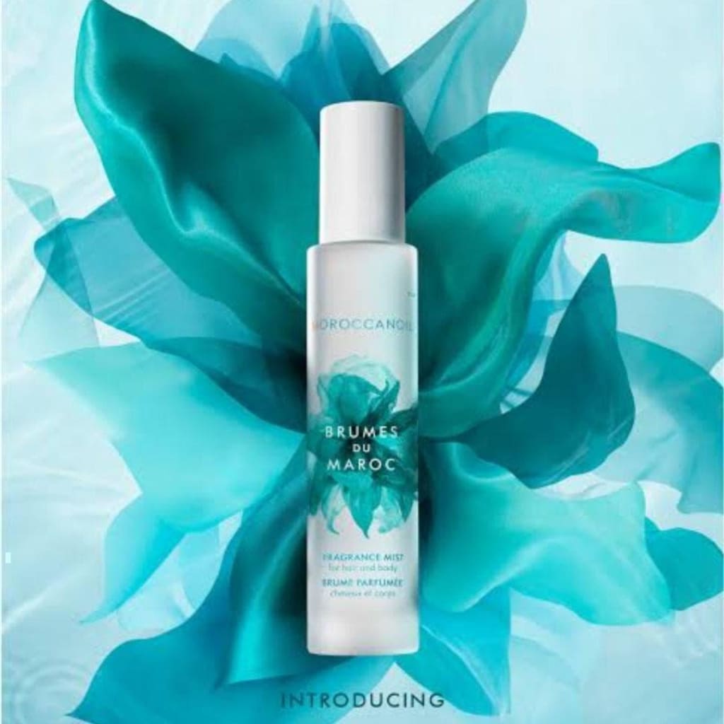 Bottle of Brumes du Maroc by Moroccanoil against flowing teal fabric with spicy amber scent