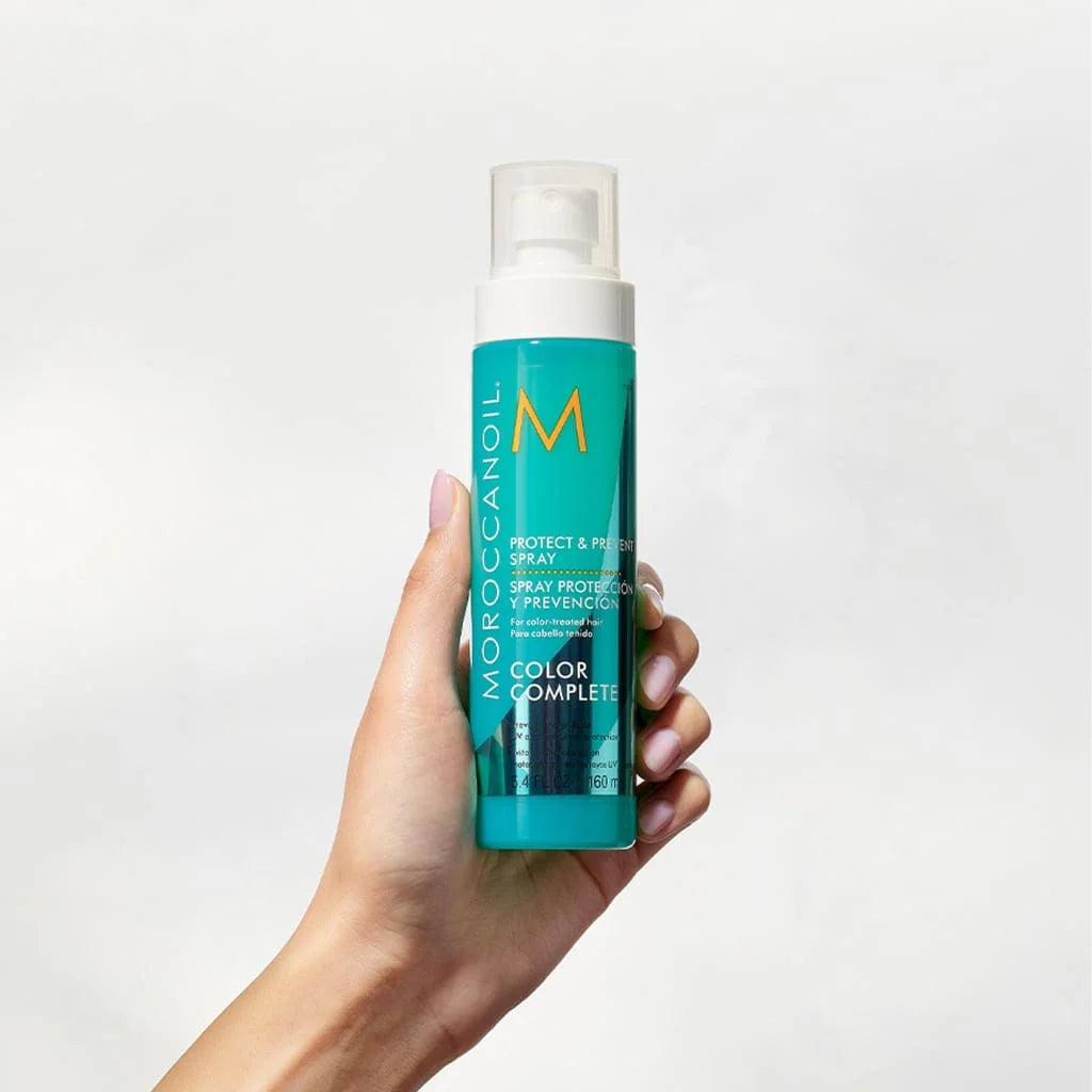 Hand holding Turquoise Moroccanoil Protect & Prevent Spray 160ml from the Color Complete line