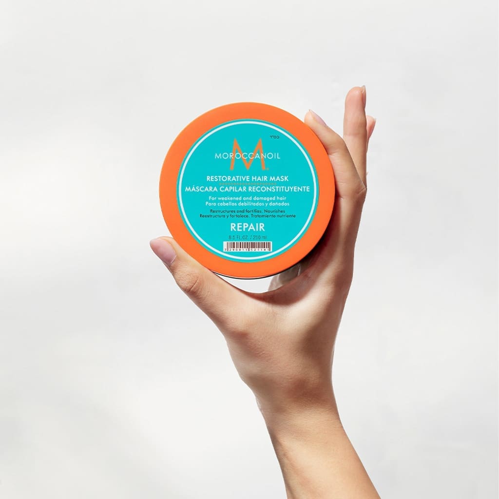 Hand holding Moroccanoil Restorative Mask 250ml for damaged hair