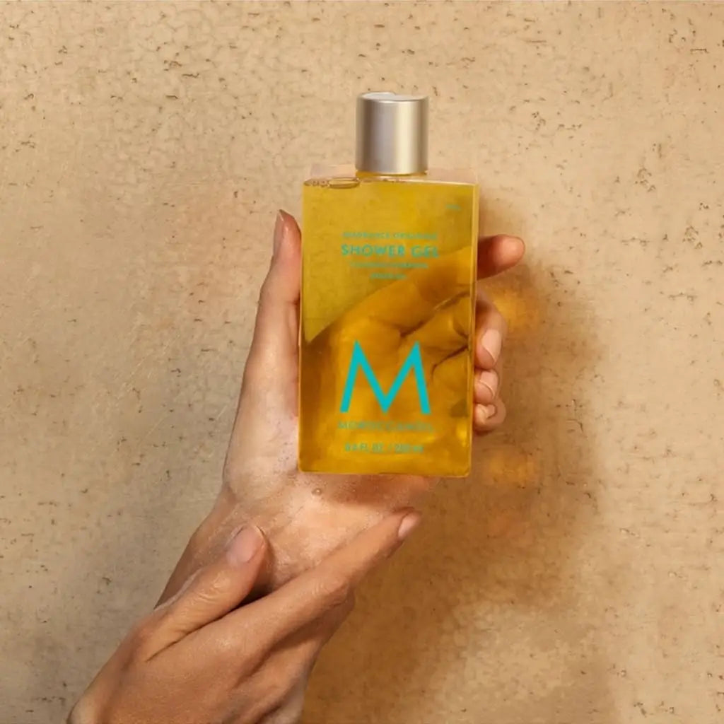 Yellow glass bottle of Moroccanoil Shower Gel Fragrance Originale 250ml with blue ’M’ logo