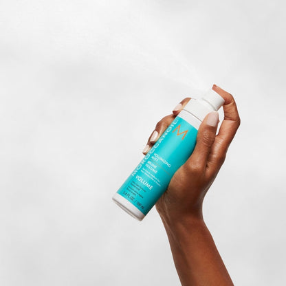 Hand holding turquoise Moroccanoil Volumizing Mist 160ML, promising long-lasting volume