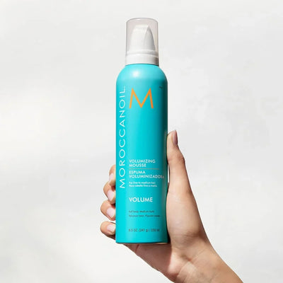 Hand holding Moroccanoil Volumizing Mousse 250ml for natural-looking styles