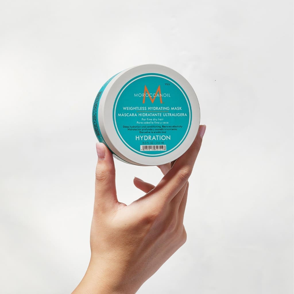 Circular container of Moroccanoil Weightless Hydrating Mask 250ml held by a hand