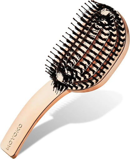 Rose gold-colored hairbrush with mixed bristles arranged in a curved pattern.