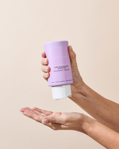 ORI Lab Blonde Conditioner: Hand holding purple bottle for blonde hair care