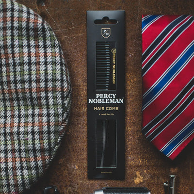 Percy Nobleman Comb & Men's Accessories: Gentleman's grooming essentials. Hair comb, tie, and cap on rustic surface.