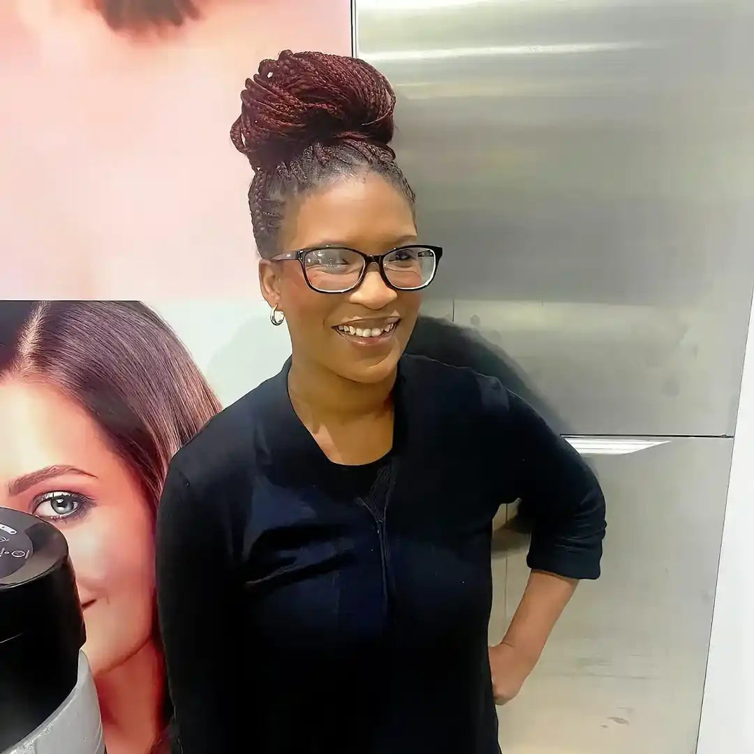 A person wearing glasses and a black top with their hair styled in an updo.