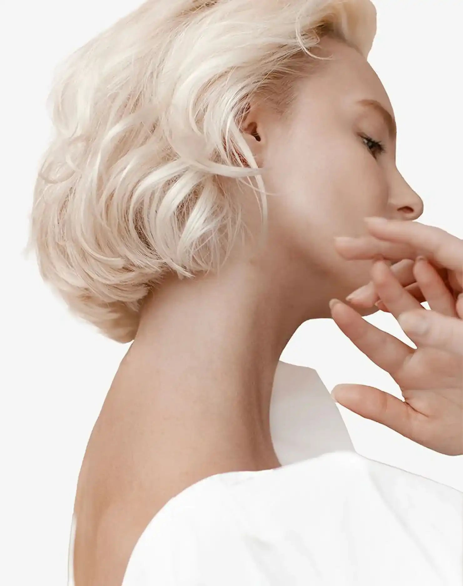 Profile view of a person with platinum blonde hair and bare shoulders.