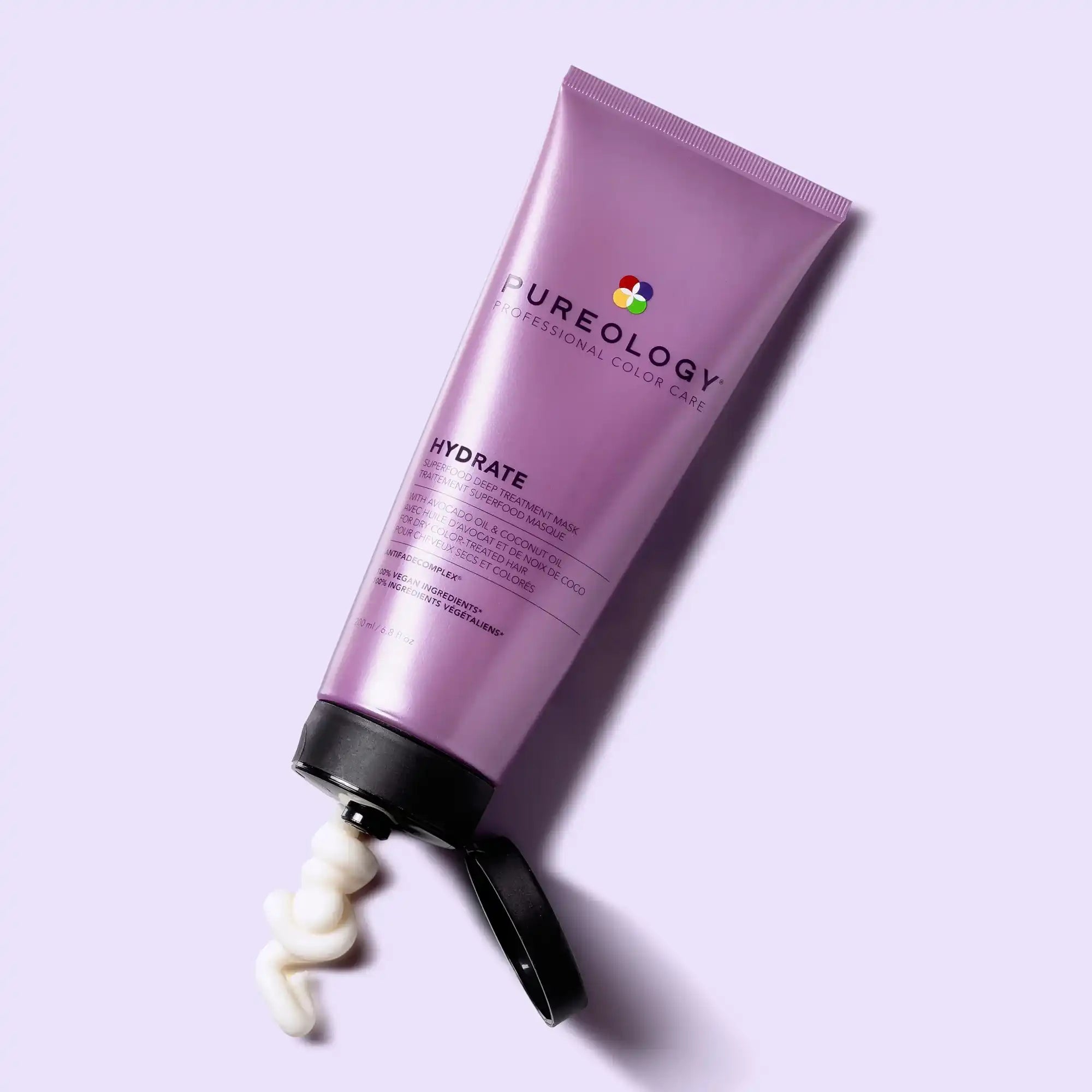 Purple tube of Pureology hair product with cream being squeezed out.