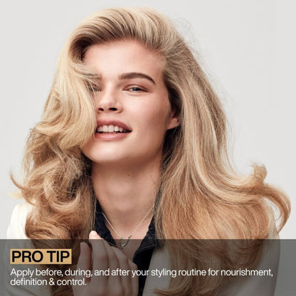 Smiling blonde woman with voluminous, styled hair using Redken All Soft Argan 6 Oil - 111ml