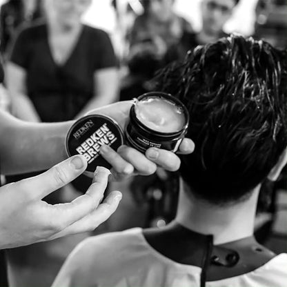 Redken Brews Maneuver Cream Pomade being applied in a salon setting for sleek hair styling