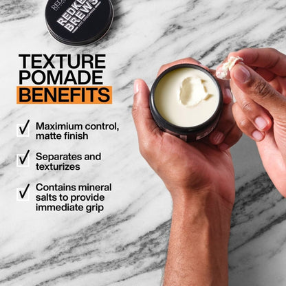 Redken Brews Outplay Texture Pomade in a 100ml black container held by a person’s hand