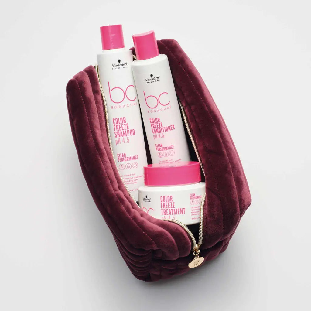 Burgundy velvet cosmetic bag containing pink-labeled hair care products.